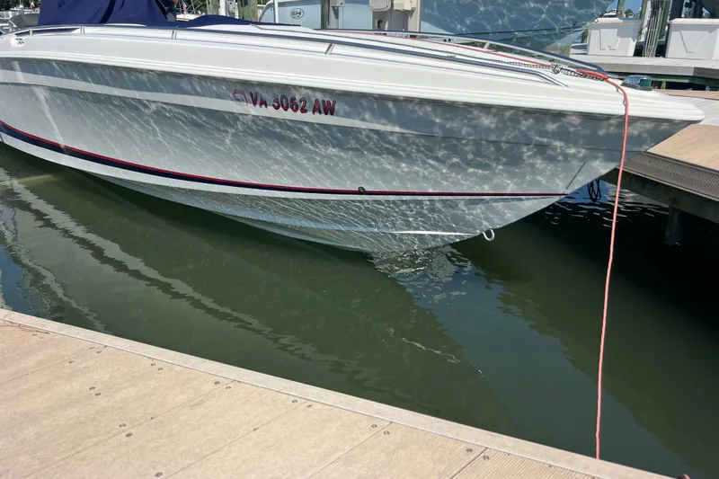 Slide: The Image of 1999 Wellcraft 302 Scarab Sport boat docked, reflecting sunlight on water. - 80