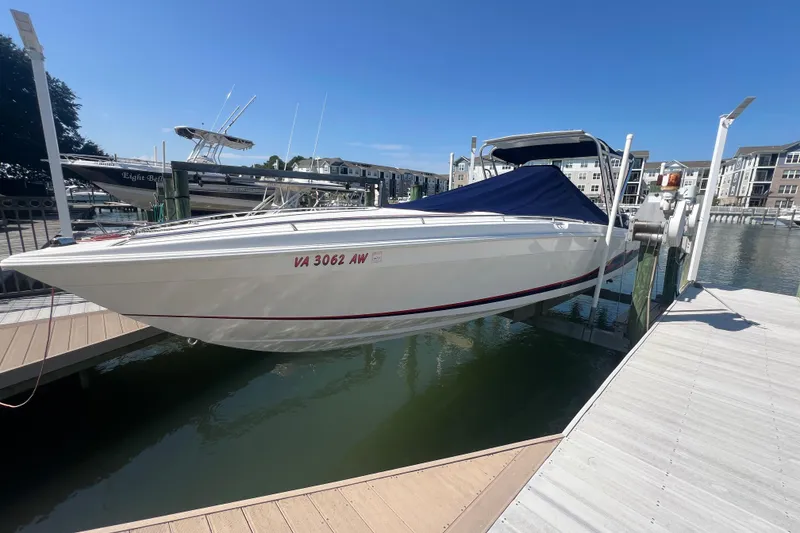 Slide: The Image of 1999 Wellcraft 302 Scarab Sport boat docked at a marina, covered and elevated. - 84