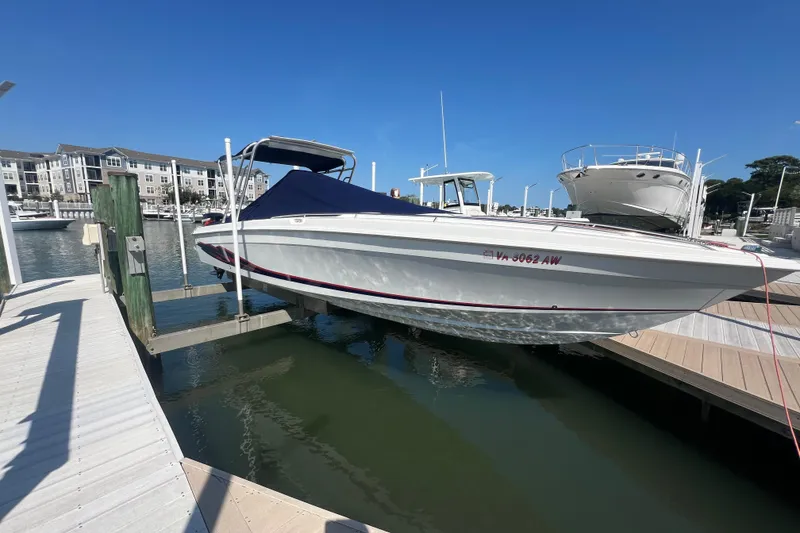 Slide: The Image of 1999 Wellcraft 302 Scarab Sport boat docked at marina under clear blue sky. - 85