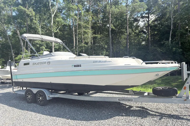 Slide: The Image of 2022 Splendor 239 Sunstar boat on trailer, parked outdoors with trees in background. - 1