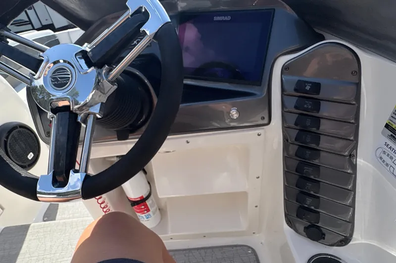 Slide: The Image of Steering wheel and dashboard of 2022 Splendor 239 Sunstar boat, featuring control panel and display. - 14