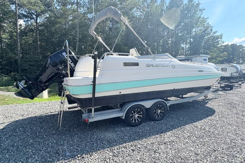 Slide: The Image of 2022 Splendor 239 Sunstar boat on trailer, parked outdoors with trees in background. - 2