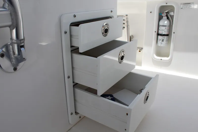Slide: The Image of Open storage drawers on a 2016 Edgewater 370CC boat, with a visible fire extinguisher. - 14