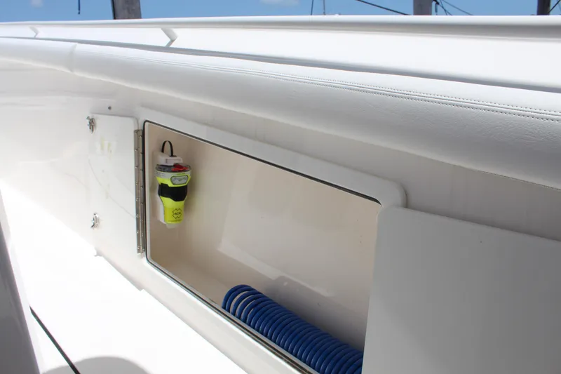 Slide: The Image of 2016 Edgewater 370CC boat storage compartment with safety equipment and coiled hose. - 24