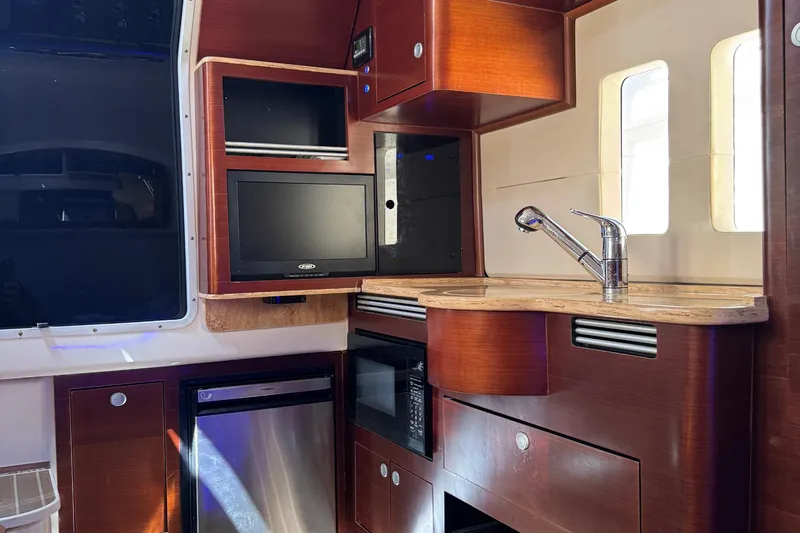 Slide: The Image of Interior of 2016 Edgewater 370CC boat with kitchenette, sink, and TV. - 47