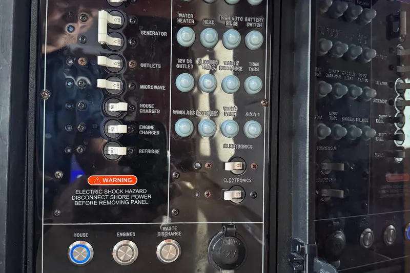 Slide: The Image of Control panel of a 2016 Edgewater 370CC boat with various switches and warning label. - 48