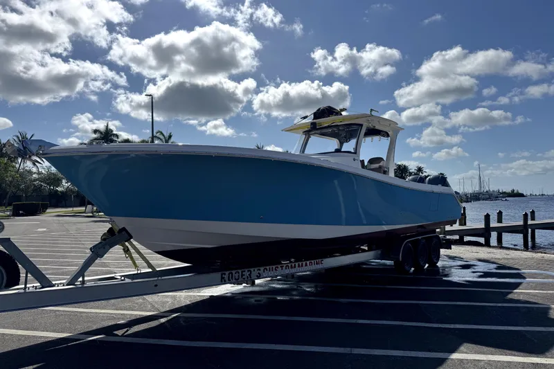 Slide: The Image of 2016 Edgewater 370CC boat on trailer, parked near waterfront under cloudy sky. - 50