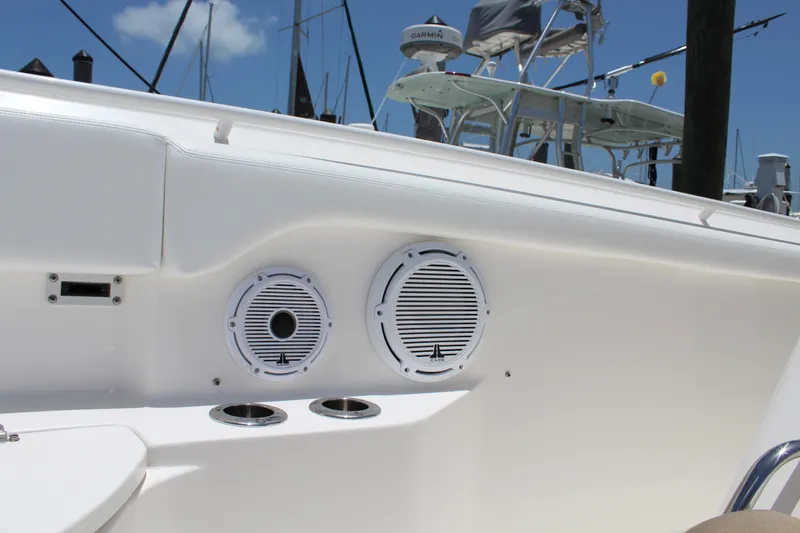 Slide: The Image of 2016 Edgewater 370CC boat interior with speakers and cup holders, docked under clear blue sky. - 9