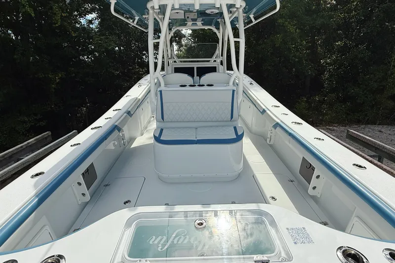 Slide: The Image of 2024 Yellowfin 36 Offshore boat interior with seating and storage, surrounded by lush greenery. - 10