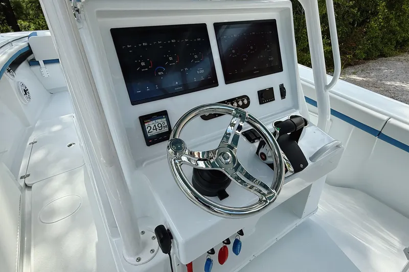 Slide: The Image of 2024 Yellowfin 36 Offshore boat dashboard with dual screens and chrome steering wheel. - 16