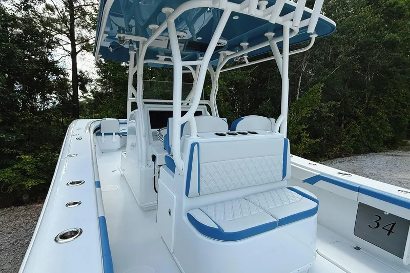 Slide: The Image of 2024 Yellowfin 36 Offshore boat interior with blue and white seating, surrounded by trees. - 17