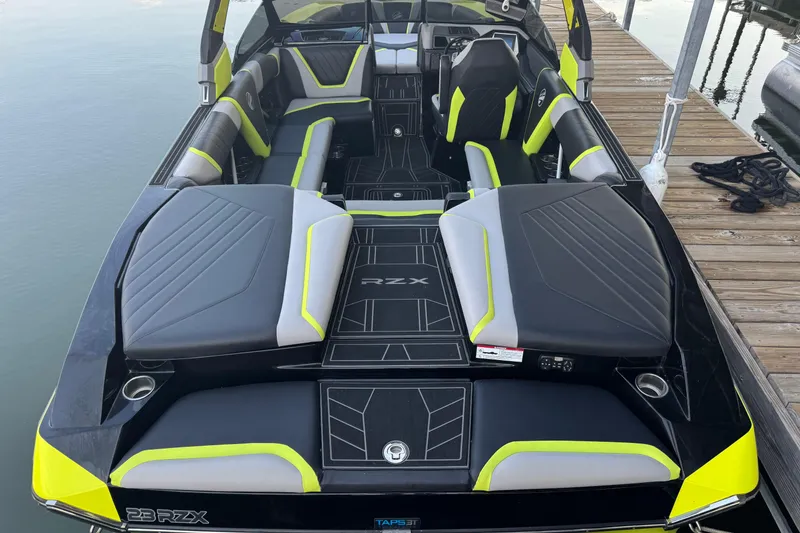Slide: The Image of 2020 Tigé 23RZX boat interior with sleek black and neon accents, docked by the water. - 2
