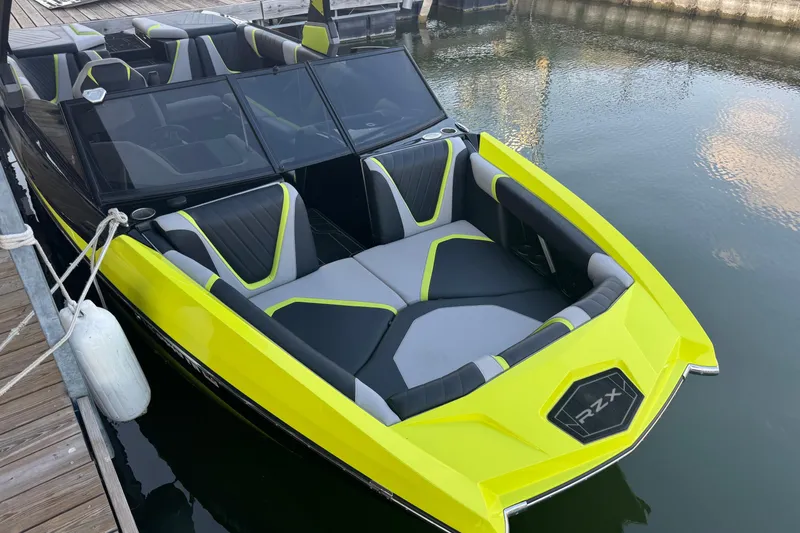 Slide: The Image of 2020 Tigé 23RZX boat with vibrant yellow and gray seating, docked by the water. - 4