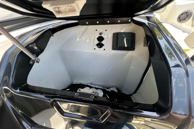 Slide: The Image of Open storage compartment of 2023 Scarab 215 ID boat, featuring sleek black and white interior. - 20