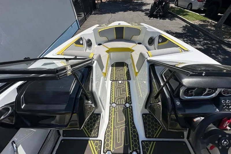 Slide: The Image of 2023 Scarab 215 ID boat interior with modern dashboard and seating, featuring yellow accents. - 22