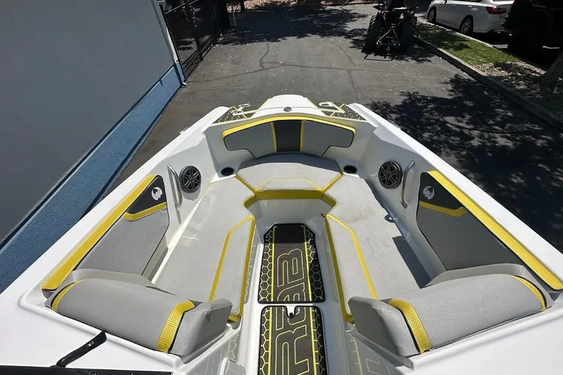 Slide: The Image of 2023 Scarab 215 ID boat interior with gray and yellow seating, outdoor setting. - 23