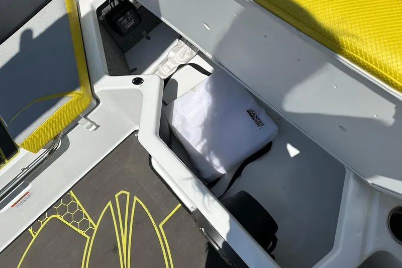 Slide: The Image of 2023 Scarab 215 ID boat interior storage compartment with yellow accents and Sea-Doo bag. - 29
