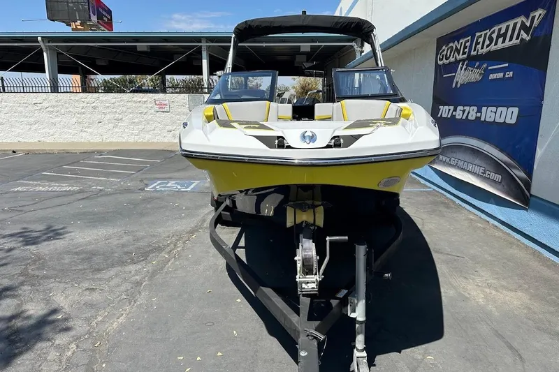 Slide: The Image of 2023 Scarab 215 ID boat in parking lot, yellow and white design, displayed at dealership. - 3