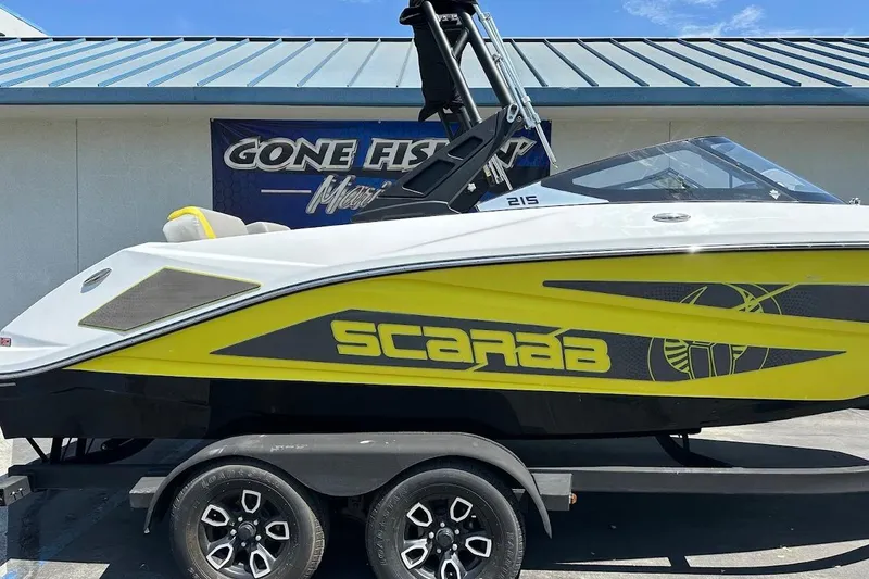 Slide: The Image of 2023 Scarab 215 ID boat with vibrant yellow and black design on a trailer. - 5