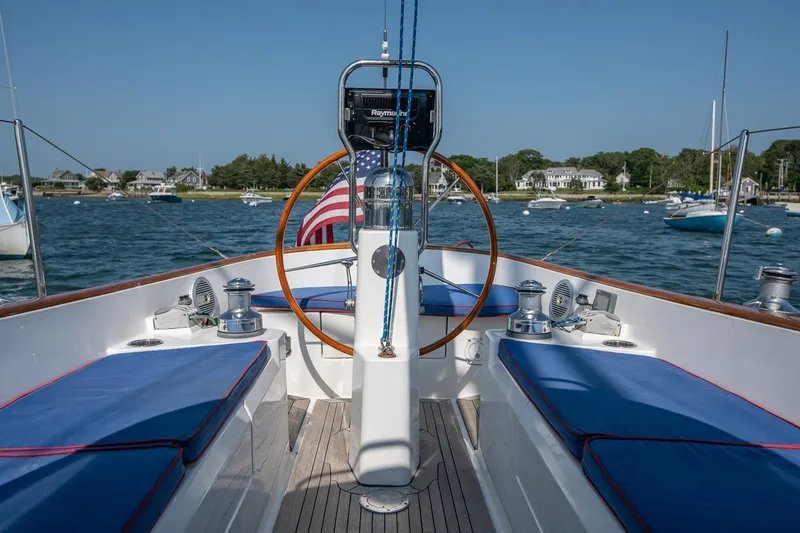 Slide: The Image of 2006 Morris M36 Daysailer cockpit with blue cushions, wooden wheel, and scenic harbor view. - 24