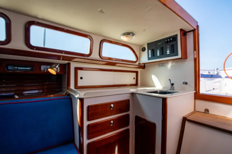 Slide: The Image of Interior of 2006 Morris M36 Daysailer, featuring wood cabinetry and compact kitchenette. - 32