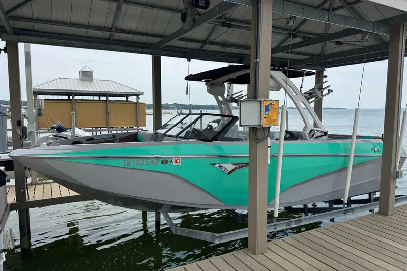 Slide: The Image of 2022 Tigé Z3 boat in turquoise, docked on a lift by the lake. - 1