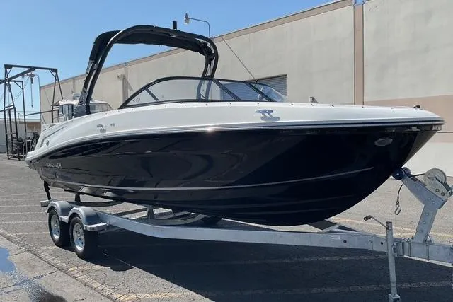 Slide: The Image of 2025 Bayliner VR6 Bowrider I/O on trailer, sleek black and white design, parked outdoors. - 4