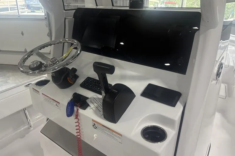 Slide: The Image of 2026 Sportsman Masters 227 boat console with steering wheel and controls in a showroom. - 26