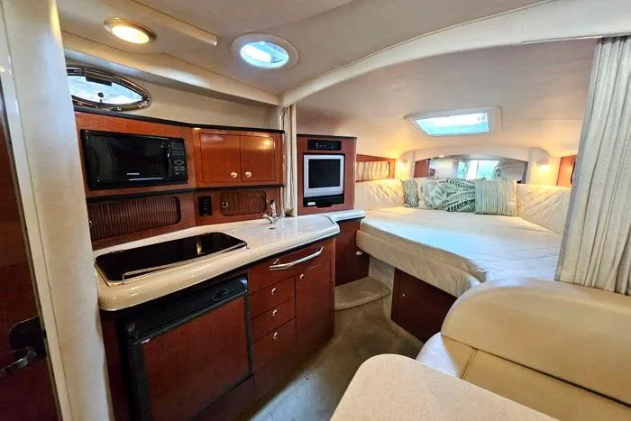 Slide: The Image of Interior of 2004 Sea Ray 300 Sundancer yacht with kitchenette and cozy sleeping area. - 15