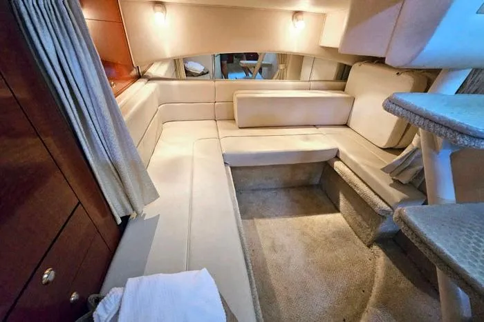 Slide: The Image of Interior of 2004 Sea Ray 300 Sundancer yacht with beige seating and cozy lighting. - 16