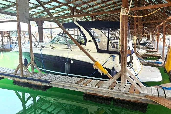 Slide: The Image of 2004 Sea Ray 300 Sundancer docked in a covered marina with green water. - 2