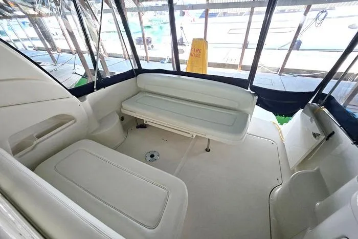 Slide: The Image of 2004 Sea Ray 300 Sundancer boat interior with white seating and enclosed deck area. - 9