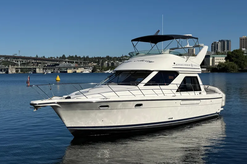 Slide: The Image of 1999 Bayliner 3788 Command Bridge Motoryacht on calm water with cityscape background. - 0