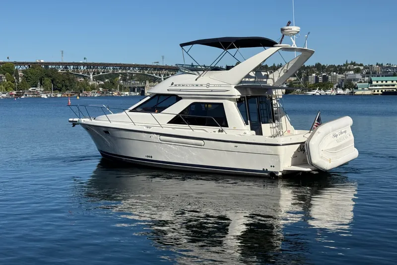 Slide: The Image of 1999 Bayliner 3788 Command Bridge Motoryacht on calm water, with cityscape background. - 1