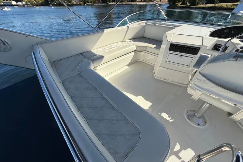 Slide: The Image of 1999 Bayliner 3788 Command Bridge Motoryacht interior with white seating and helm, on calm water. - 17