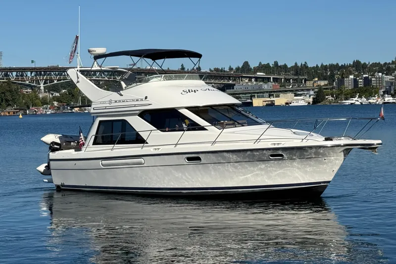 Slide: The Image of 1999 Bayliner 3788 Command Bridge Motoryacht on calm water, cityscape background. - 3