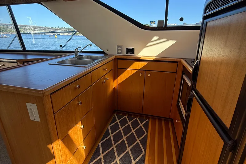 Slide: The Image of 1999 Bayliner 3788 Command Bridge Motoryacht kitchen with wooden cabinets and waterfront view. - 33