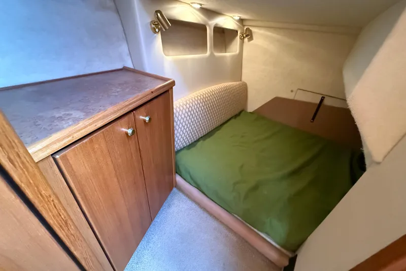 Slide: The Image of 1999 Bayliner 3788 Command Bridge Motoryacht cabin with bed, wooden cabinet, and soft lighting. - 38