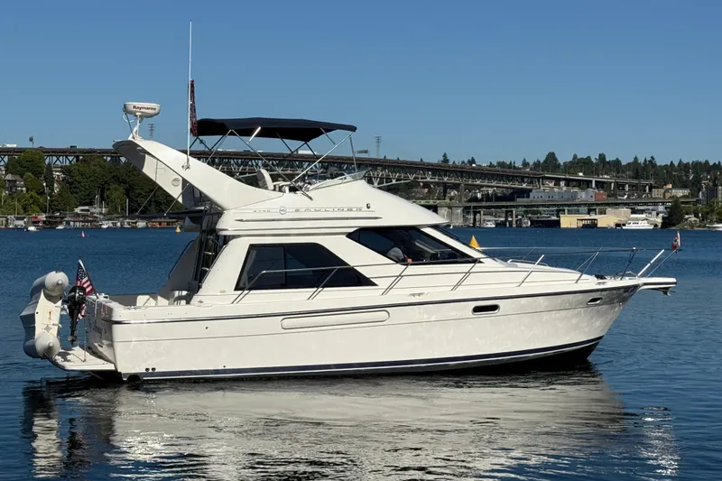 Slide: The Image of 1999 Bayliner 3788 Command Bridge Motoryacht on calm water, with bridge and trees in background. - 6