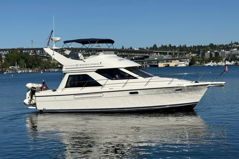 Slide: The Image of 1999 Bayliner 3788 Command Bridge Motoryacht on calm water, cityscape background. - 7