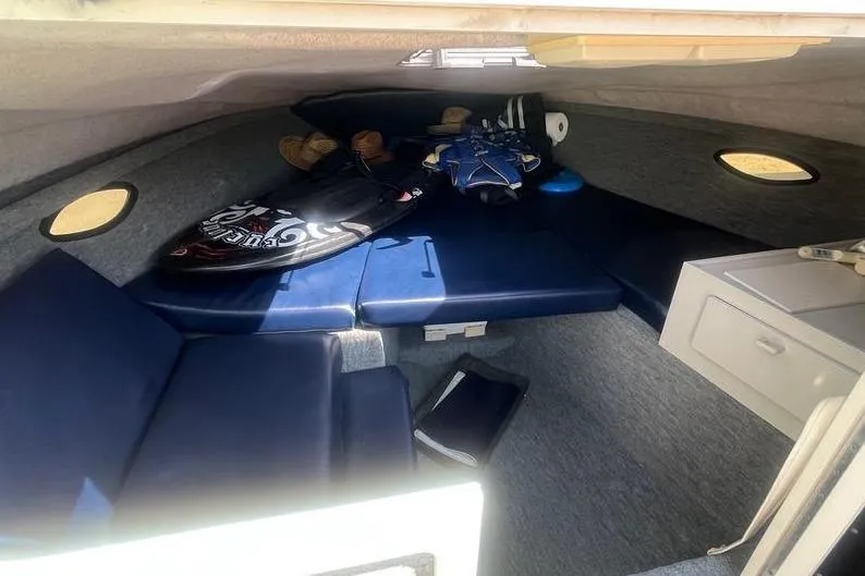 Slide: The Image of 1997 Reinell 240 boat cabin interior with blue cushions and storage compartments. - 18