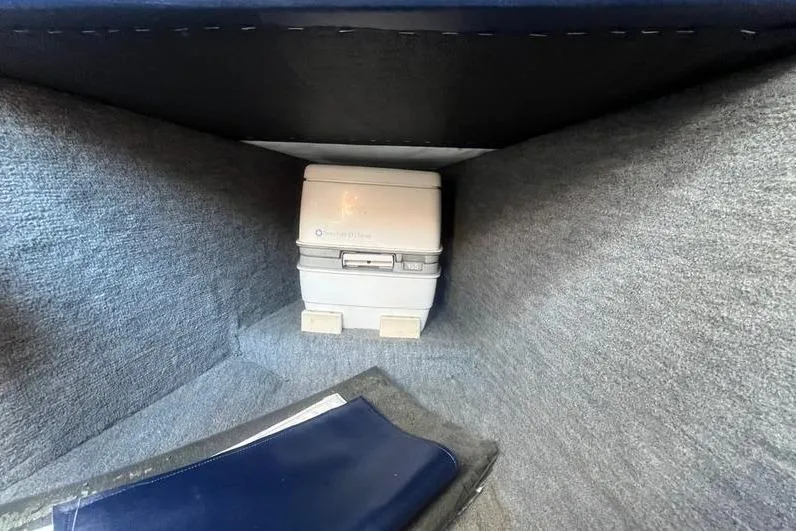 Slide: The Image of 1997 Reinell 240 boat interior with portable toilet and storage compartment. - 22