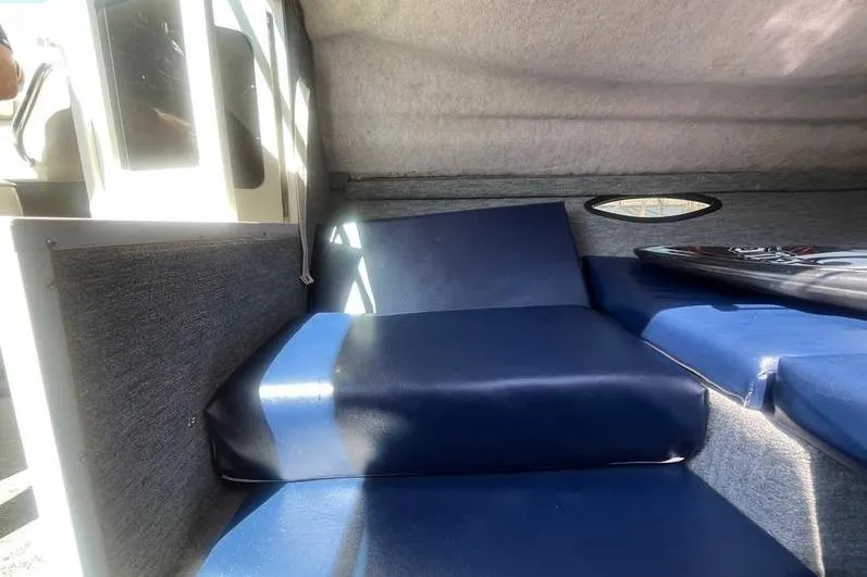 Slide: The Image of Interior cabin of a 1997 Reinell 240 boat with blue seating and sunlight. - 24