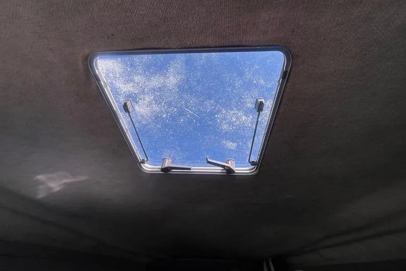 Slide: The Image of Boat hatch view from inside a 1997 Reinell 240, showing blue sky and clouds. - 25