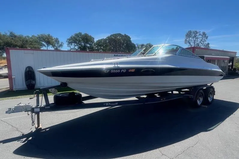Slide: The Image of 1997 Reinell 240 boat on trailer, parked outdoors under clear blue sky. - 28