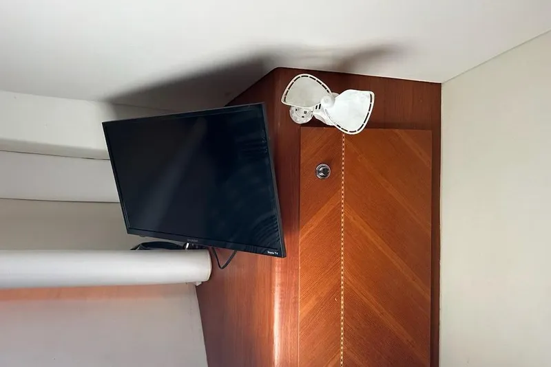 Slide: The Image of Wall-mounted TV and fan inside a 2001 Jupiter 35 Convertible boat cabin. - 22