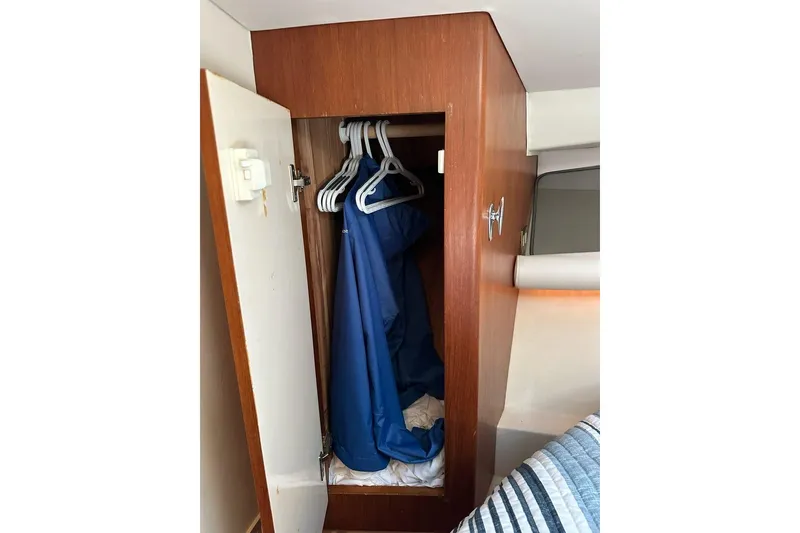 Slide: The Image of Wooden closet with blue jackets on hangers inside a 2001 Jupiter 35 Convertible boat. - 23