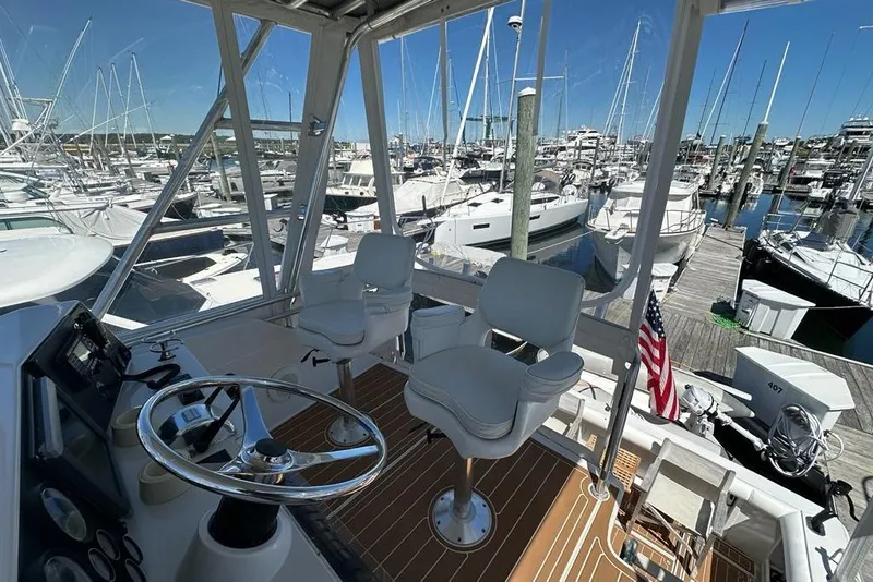 Slide: The Image of Helm of 2001 Jupiter 35 Convertible yacht at marina, featuring steering wheel and seating. - 36