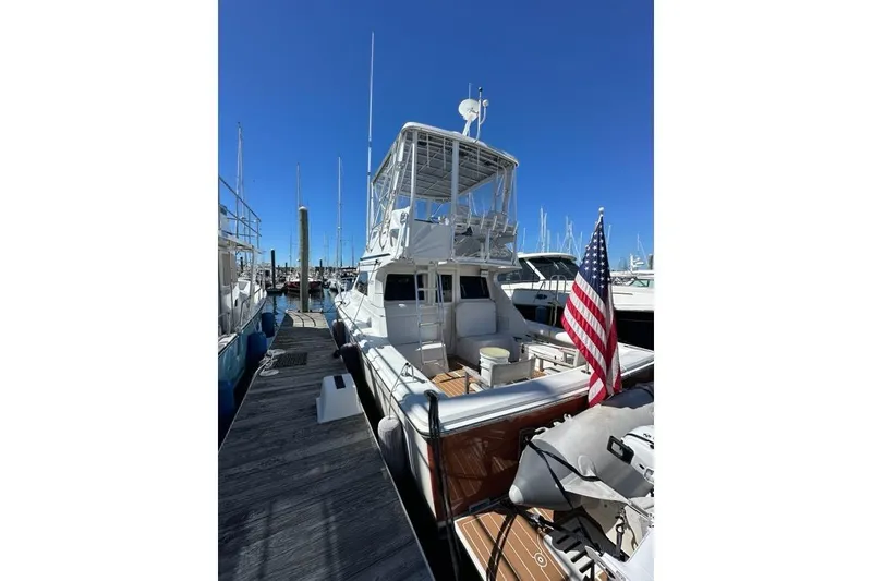Slide: The Image of 2001 Jupiter 35 Convertible yacht docked, featuring American flag and clear blue sky. - 7