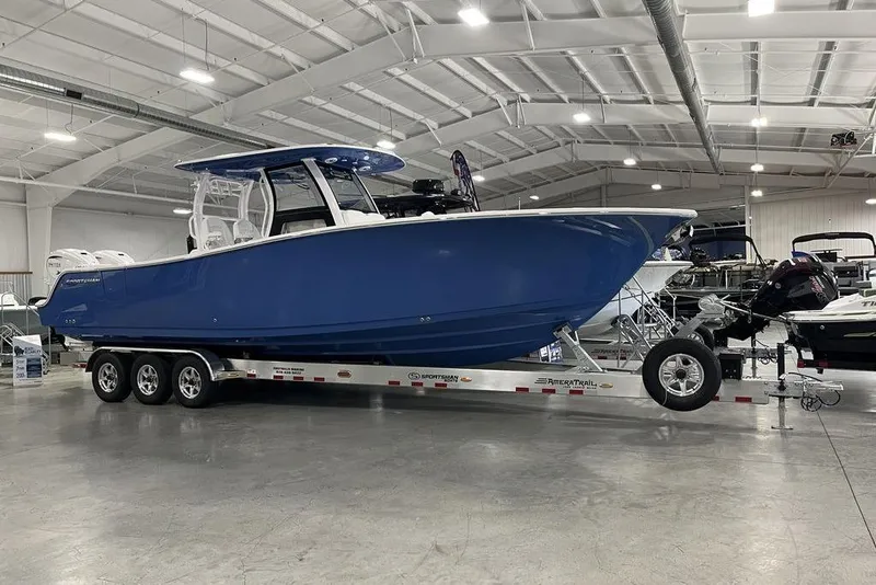 The Image of 2026 Sportsman Heritage 321 Center Console boat in showroom, blue hull, on trailer. - 3